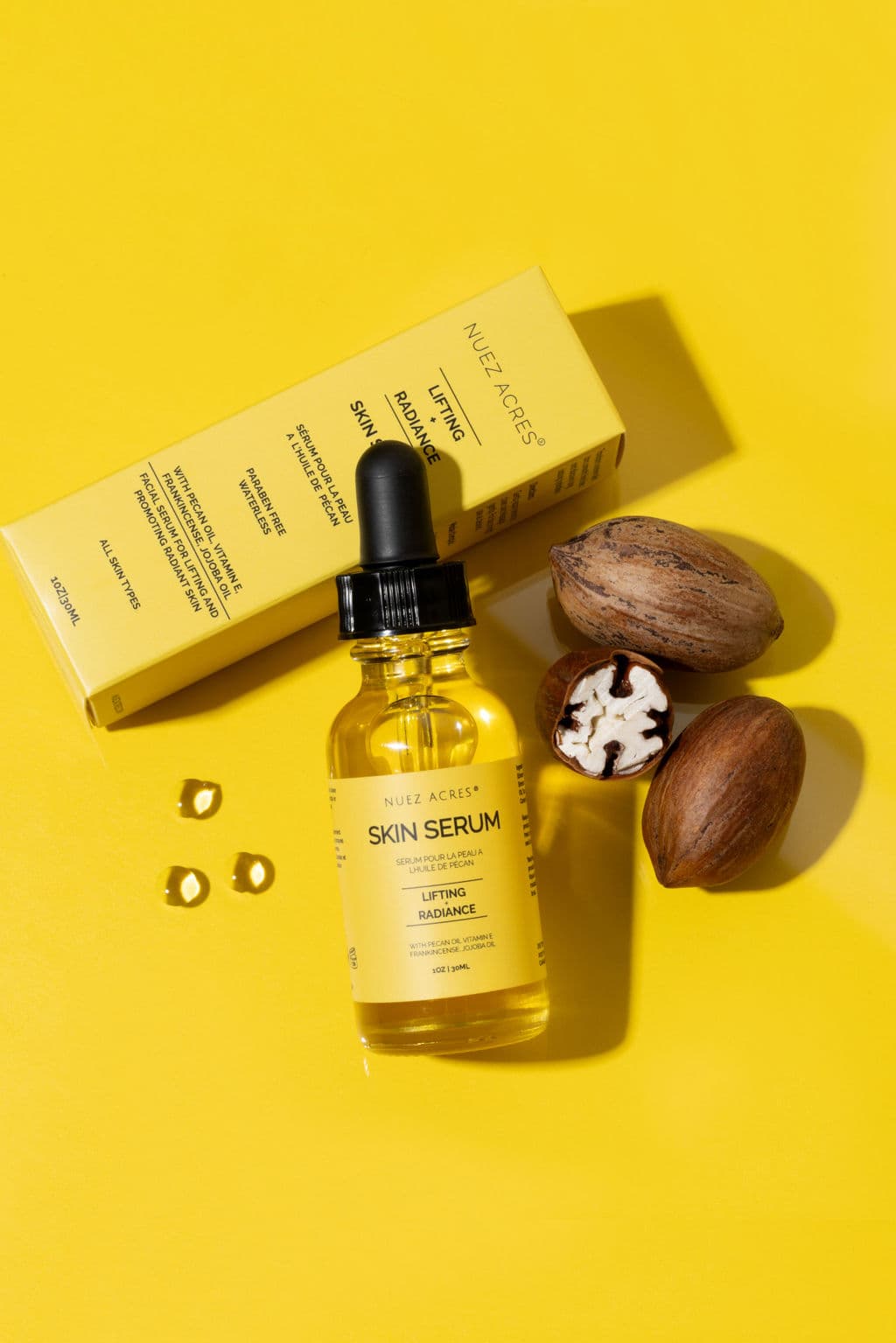 Nuez Acres Skin Serum bottle and packaging with pecans on a yellow background